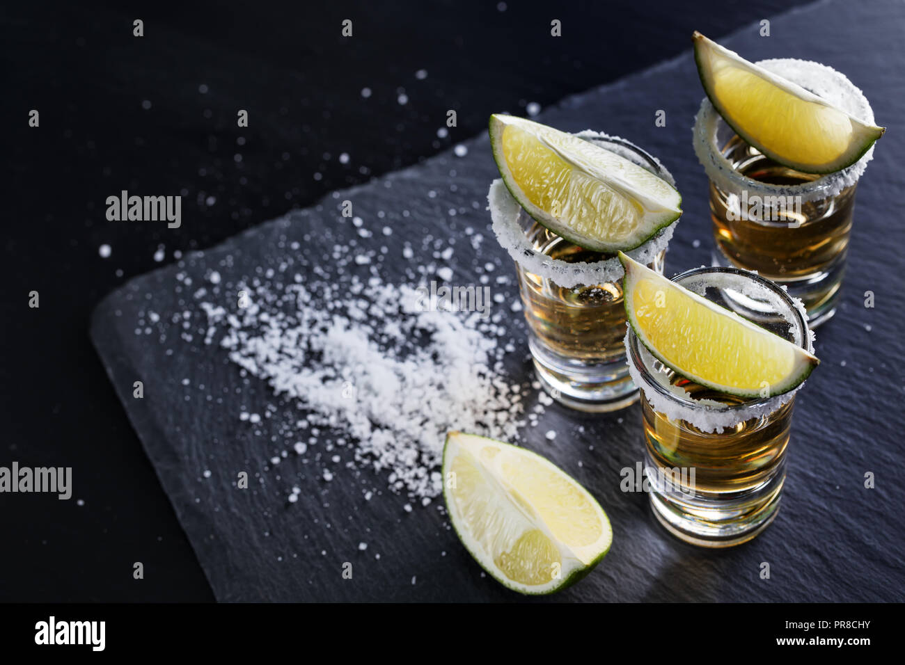 Drei Gläser Tequila mit Salz auf der Felge und Kalk auf schwarzen Hintergrund. Alkoholfreien Cocktail. Mexikanische traditionelle Getränk Stockfoto