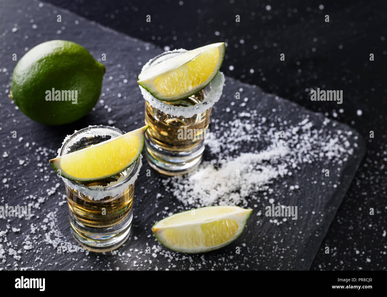 Zwei Gläser mit Tequila und Kalk auf schwarzem Hintergrund. Alkoholfreien Cocktail. Mexikanische traditionelle Getränk Stockfoto