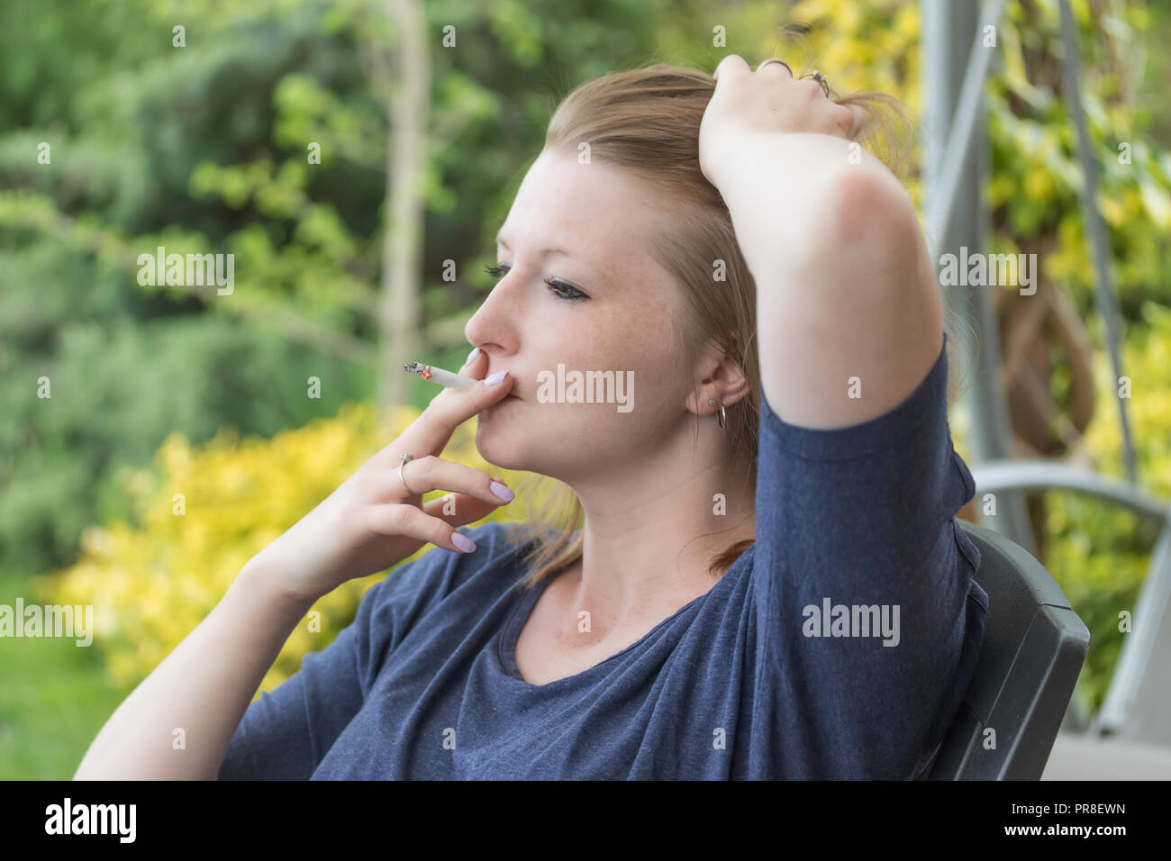 Seitenansicht der kaukasischen Langhaarige junge brünette Frau rauchen Zigarette im Freien. Stockfoto