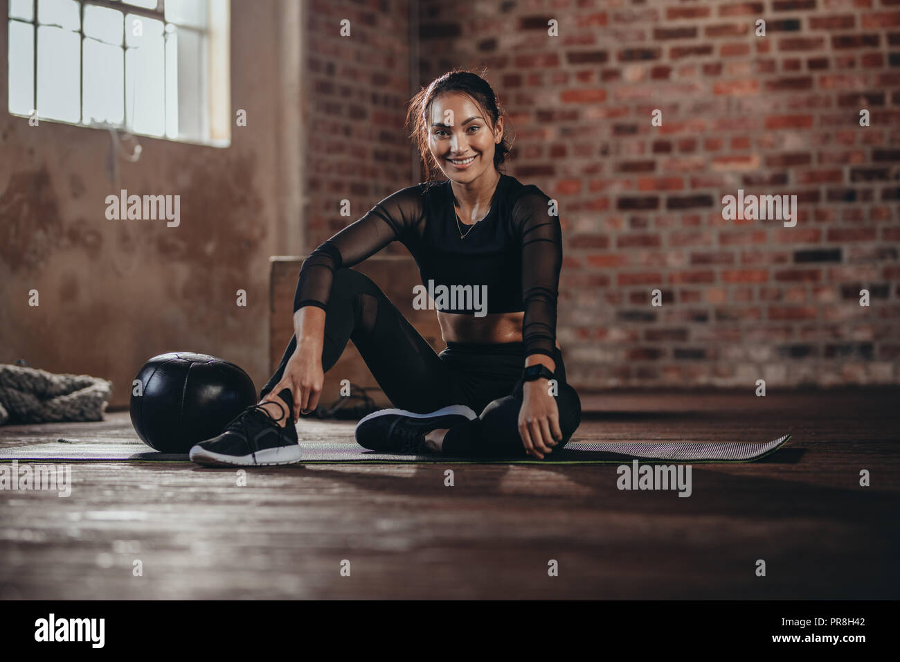 Porträt einer jungen Frau während einer Pause in der Turnhalle. Hispanischen Frauen sitzen auf dem Boden an der Kamera suchen, Ausruhen nach Training. Stockfoto