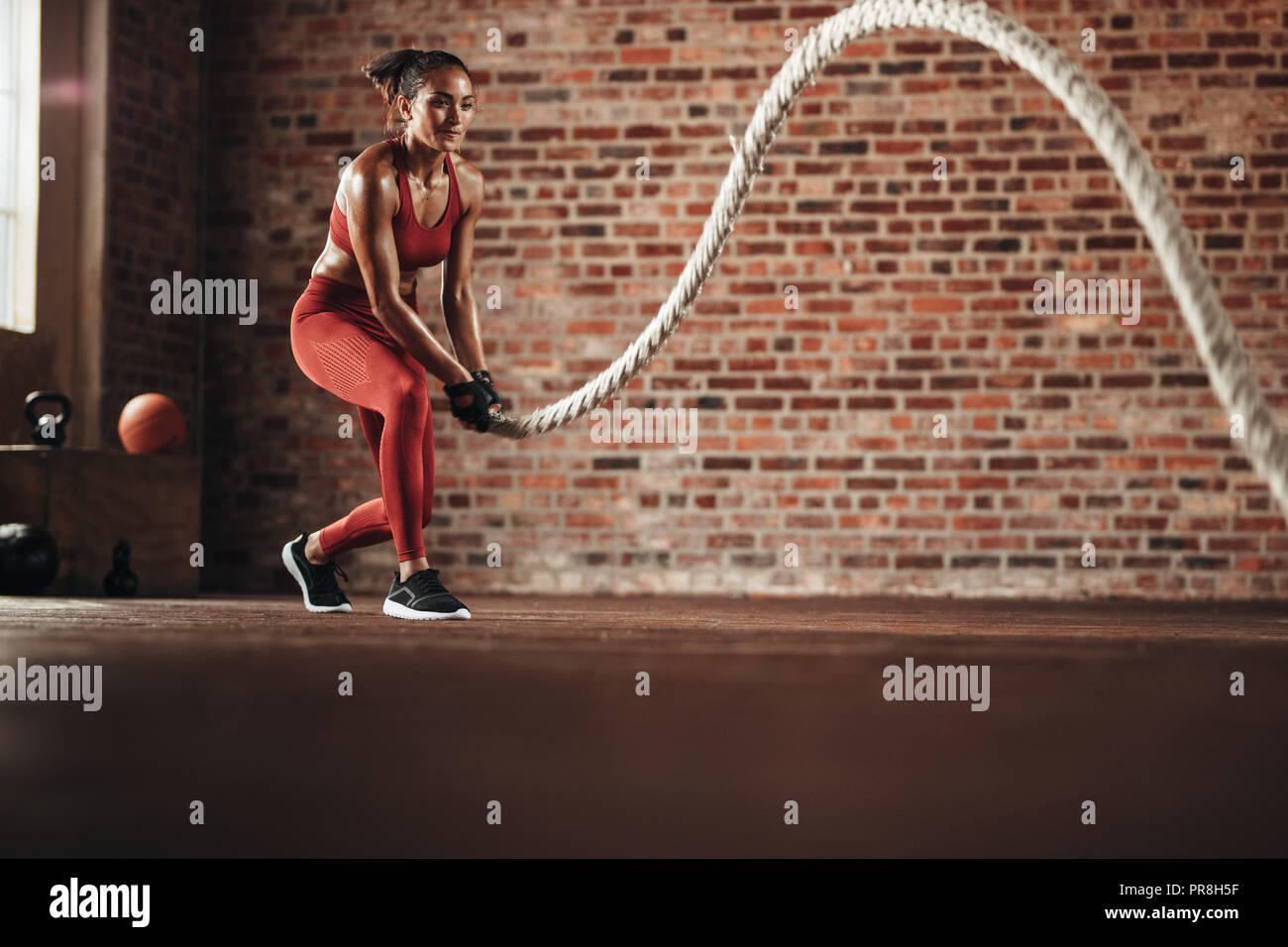 Frau mit Ausbildung Seil für die Übung an der Turnhalle. Athleten, die die Arbeit mit Schlacht Seil Cross Training Gym. Stockfoto