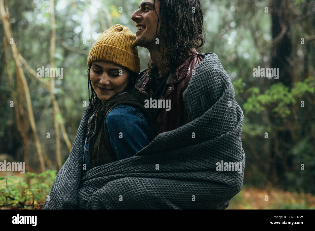 Junges Paar ihre romantische Datum genießen, wie Sie in der erfrischenden Regen stehen. Junge Liebhaber genießen den Regen im Wald. Stockfoto