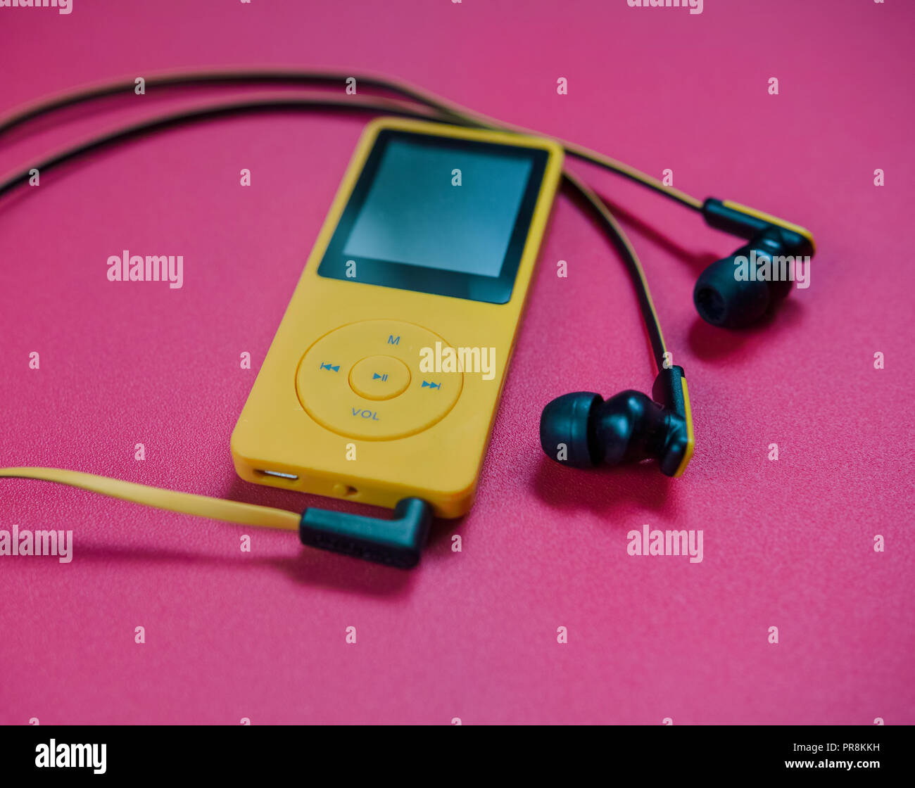 Eine gelbe MP3 Media Player, mit Kopfhörern auf eine rote Fläche. Stockfoto