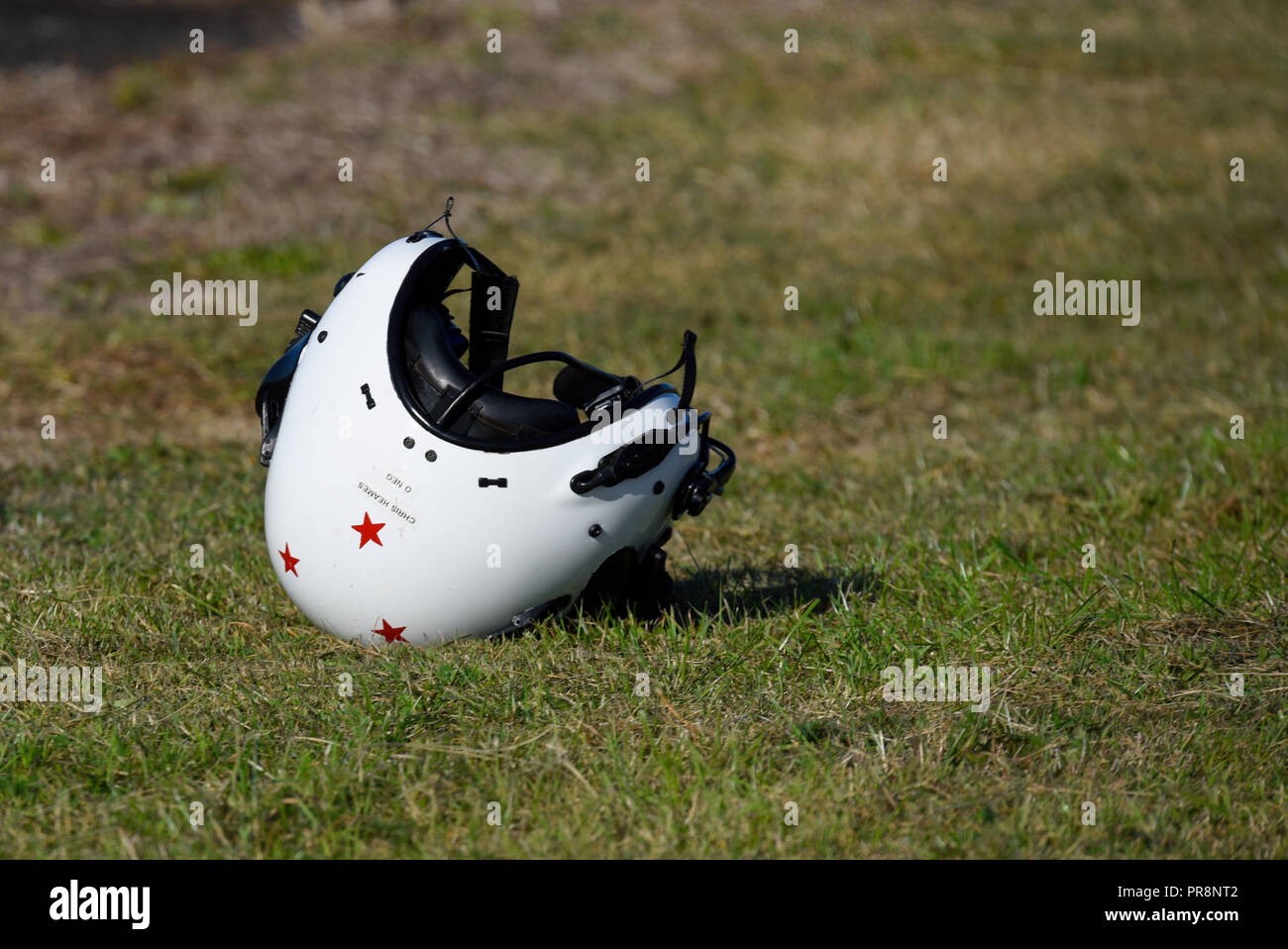 Der Pilotenhelm sitzt, liegt vor oder nach dem Flug auf dem Boden. Fliegender Helm in Isolation. Isoliert. Rote Sterne. Chris Heames und Blutgruppe Stockfoto