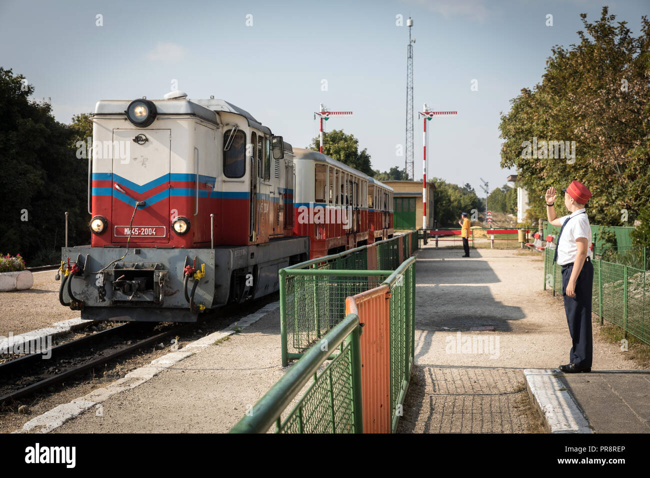 Ein Mitglied des Personals begrüßt als ein Zug kommt an Bahnhof Széchenyi-hegy auf die kinderbahn in Budapest Stockfoto