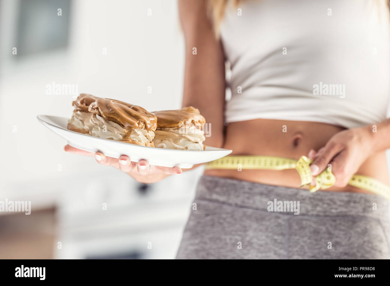 Der sport Bild einer attraktiven Frau Halteplatte mit hohem Kalorien- Kuchen und Maßband. Stockfoto