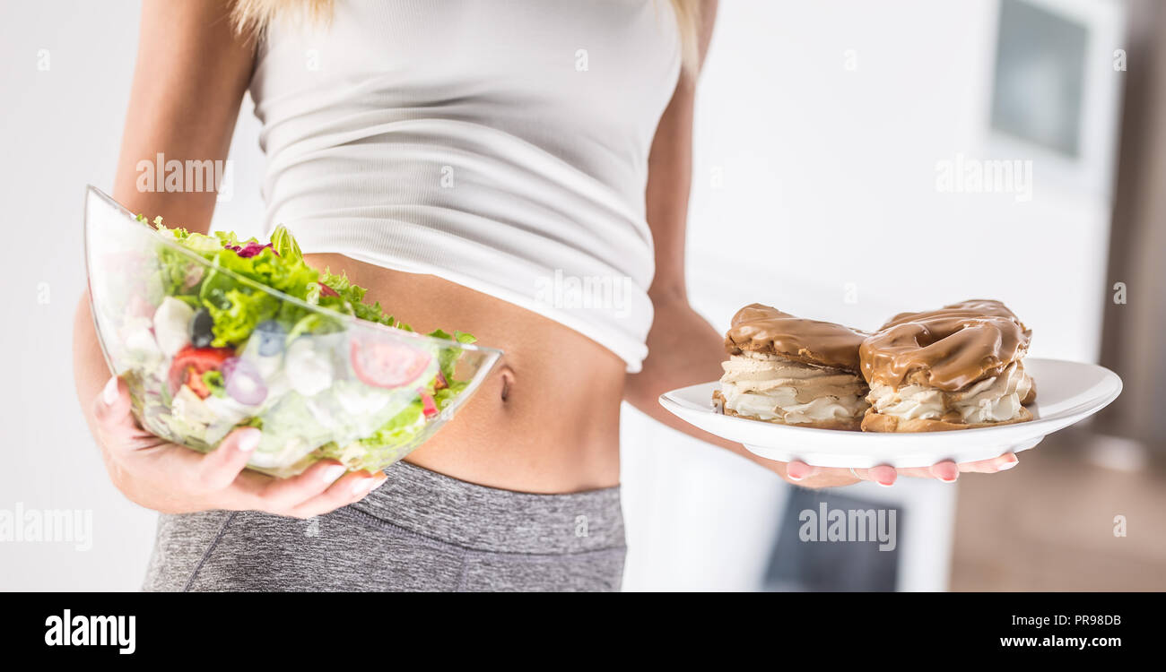 Der sport Bild einer attraktiven Frau Halteplatte mit hohem Kalorien- Kuchen und frischen Salat. Stockfoto