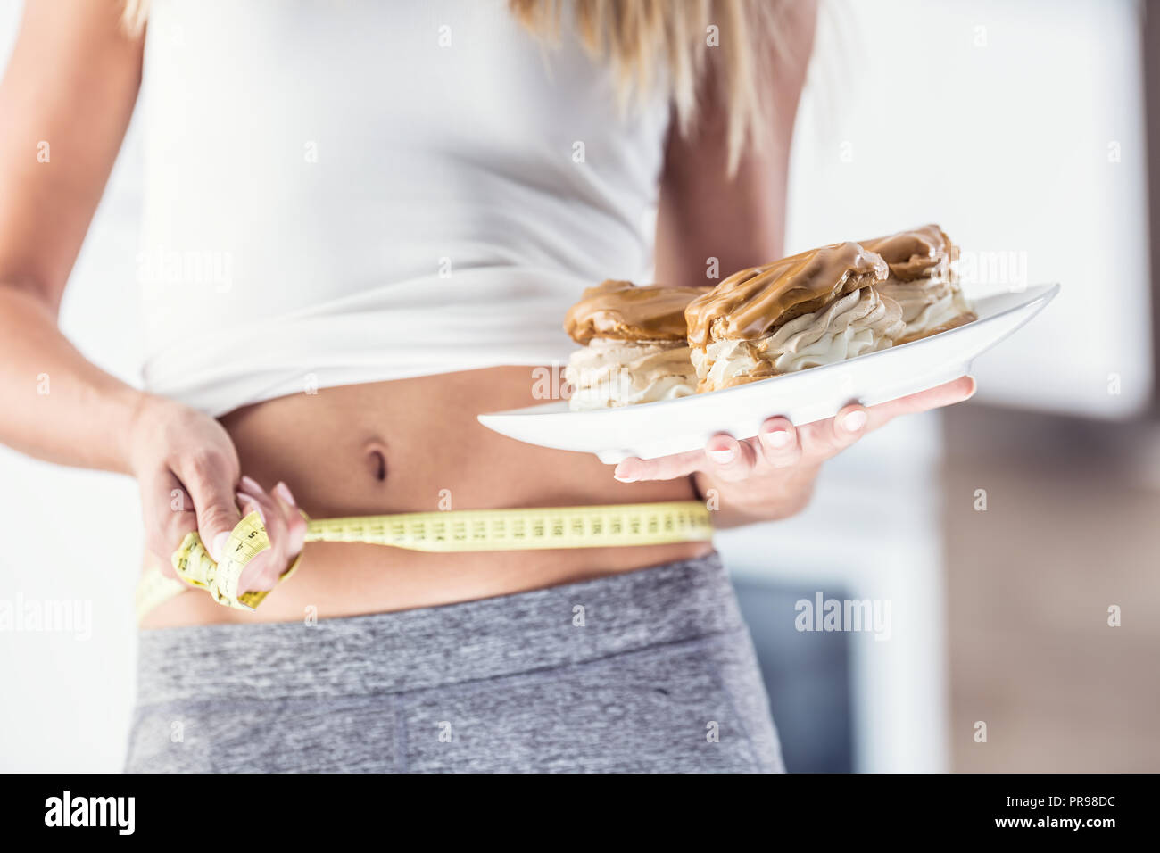 Der sport Bild einer attraktiven Frau Halteplatte mit hohem Kalorien- Kuchen und Maßband. Stockfoto