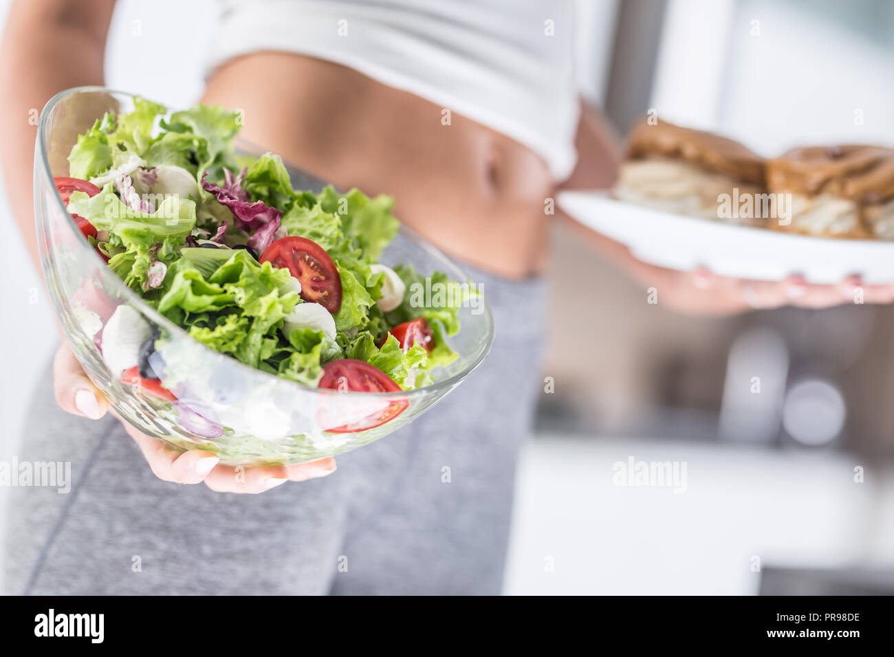 Der sport Bild einer attraktiven Frau Halteplatte mit hohem Kalorien- Kuchen und frischen Salat. Stockfoto