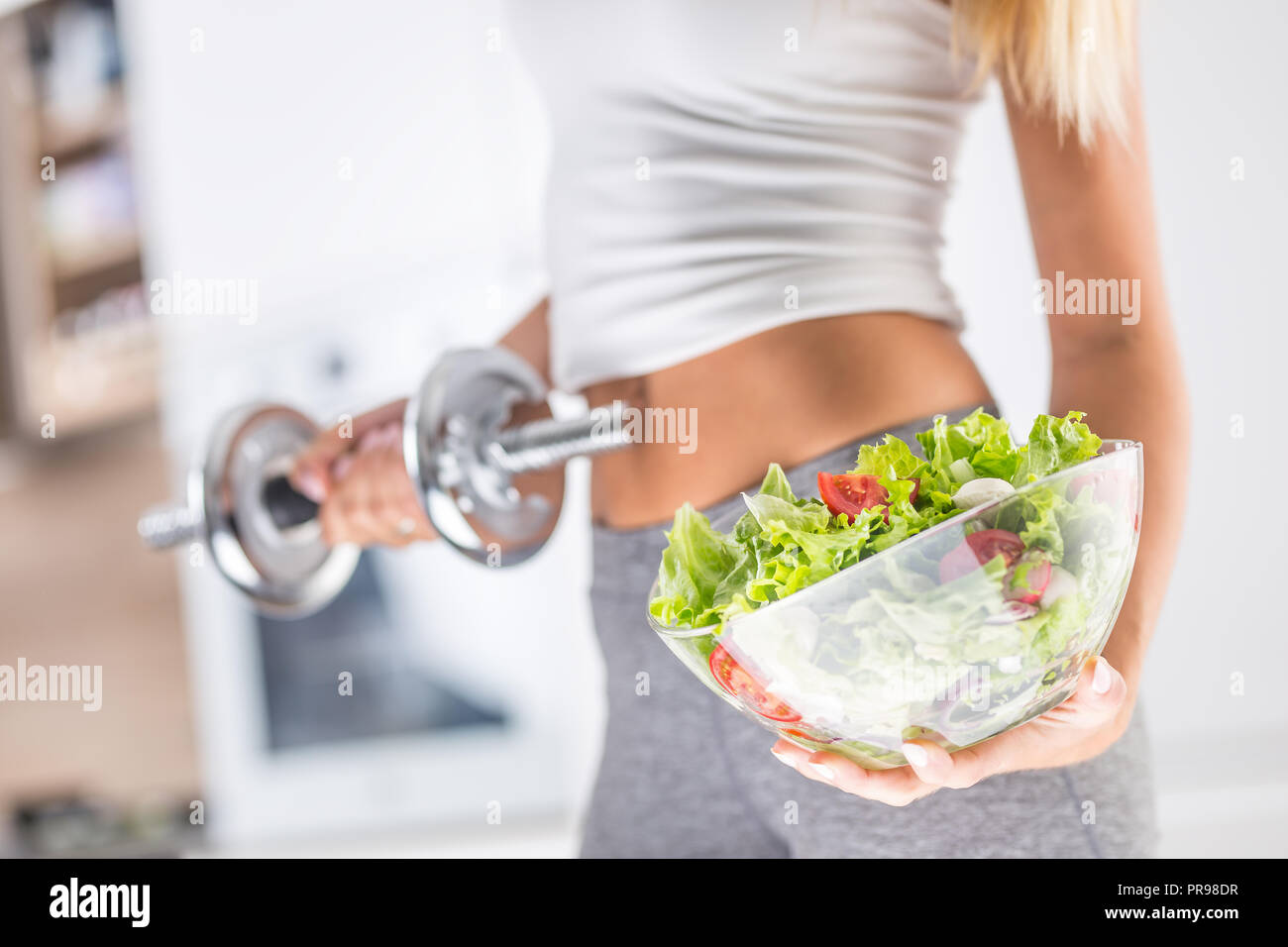 Der sport Bild einer attraktiven Frau mit Schale aus frischem Gemüse und Salat Hantel. Stockfoto