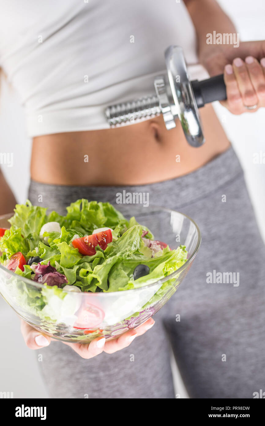Der sport Bild einer attraktiven Frau mit Schale aus frischem Gemüse und Salat Hantel. Stockfoto
