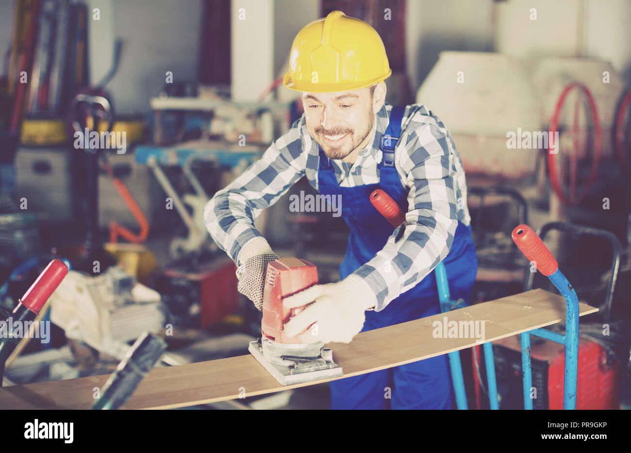 Mann 26-30 Jahre alt wird mit Schleifer für Bauarbeiten am Workshop. Stockfoto