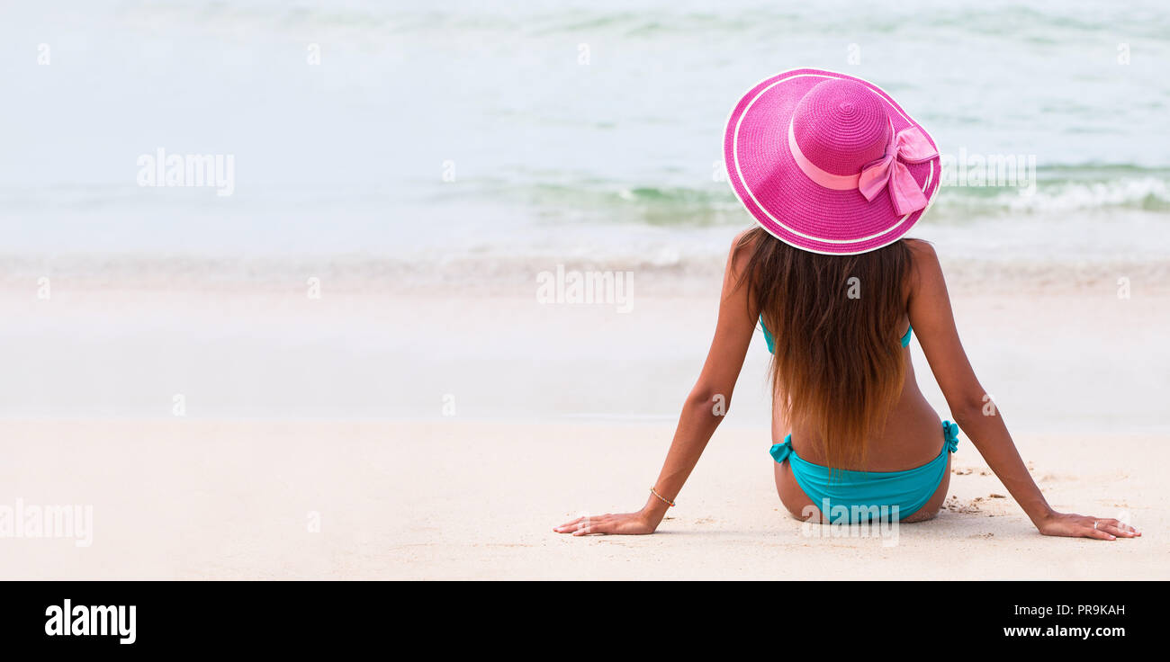 Frau in großen Hut sitzt am Strand am Meer Stockfoto