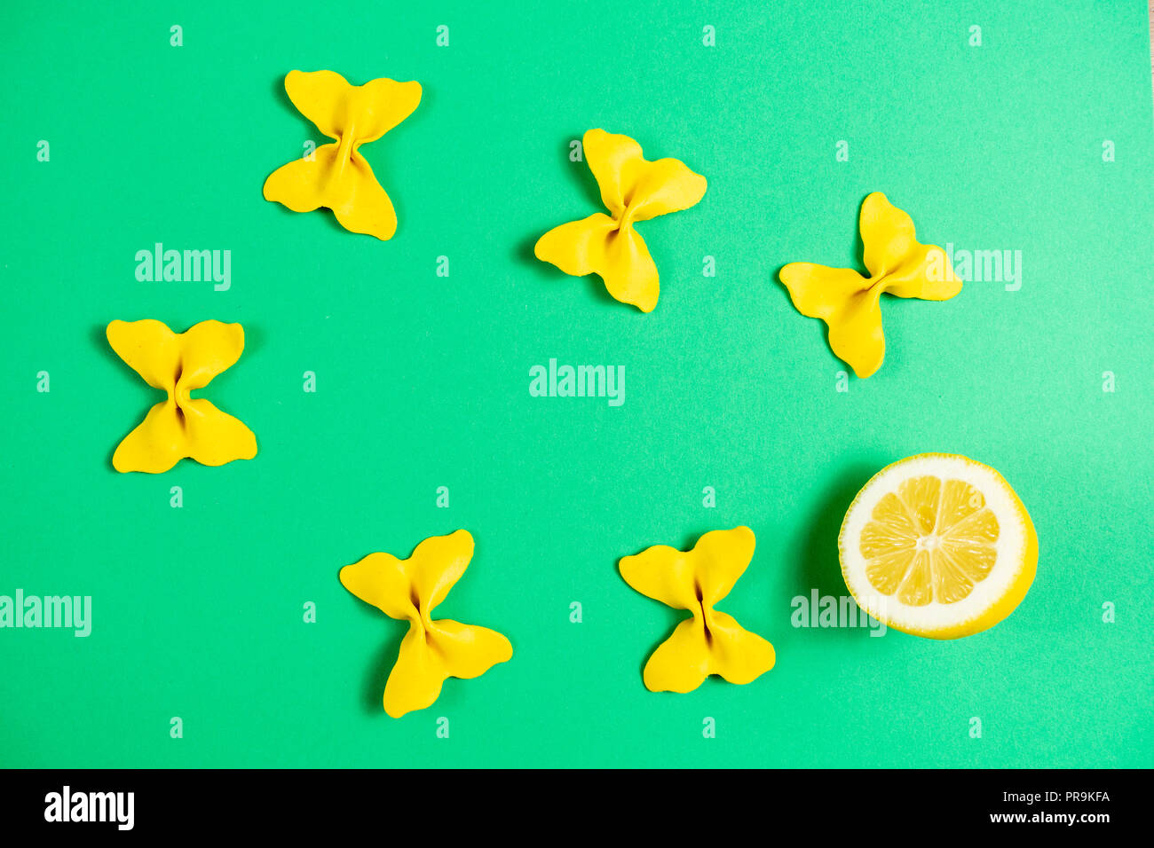 Kreative Sommer Layout aus Zitrone und farbigen Nudeln Grieß Papillon auf hell grün hinterlegt. Obst minimalen Begriff Stockfoto