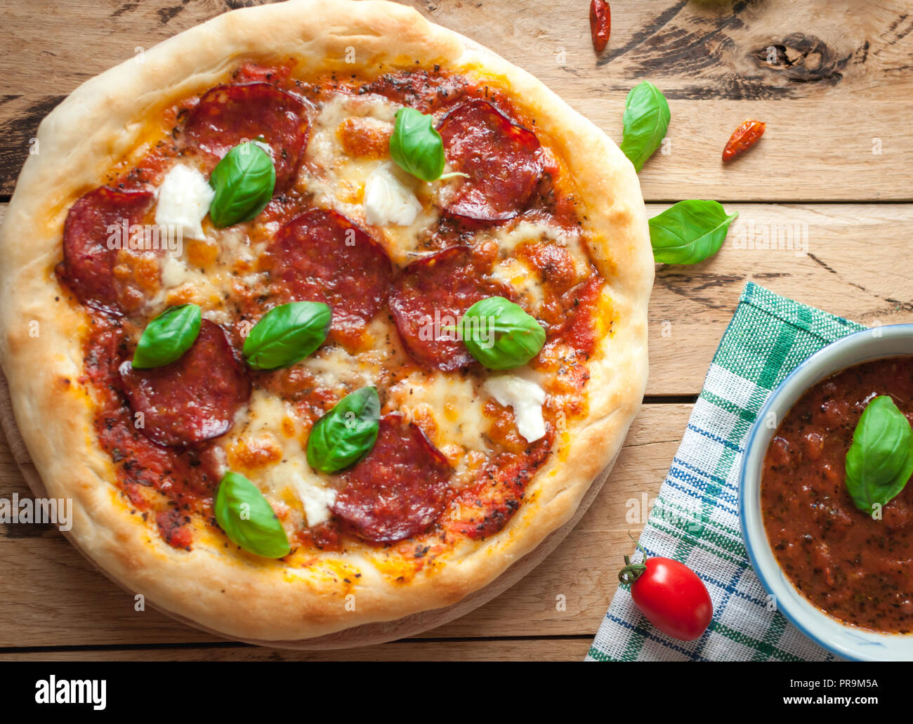 Nahaufnahme der hausgemachten rustikale Pizza mit Salami, Mozzarella und frischem Basilikum, Ansicht von oben Stockfoto