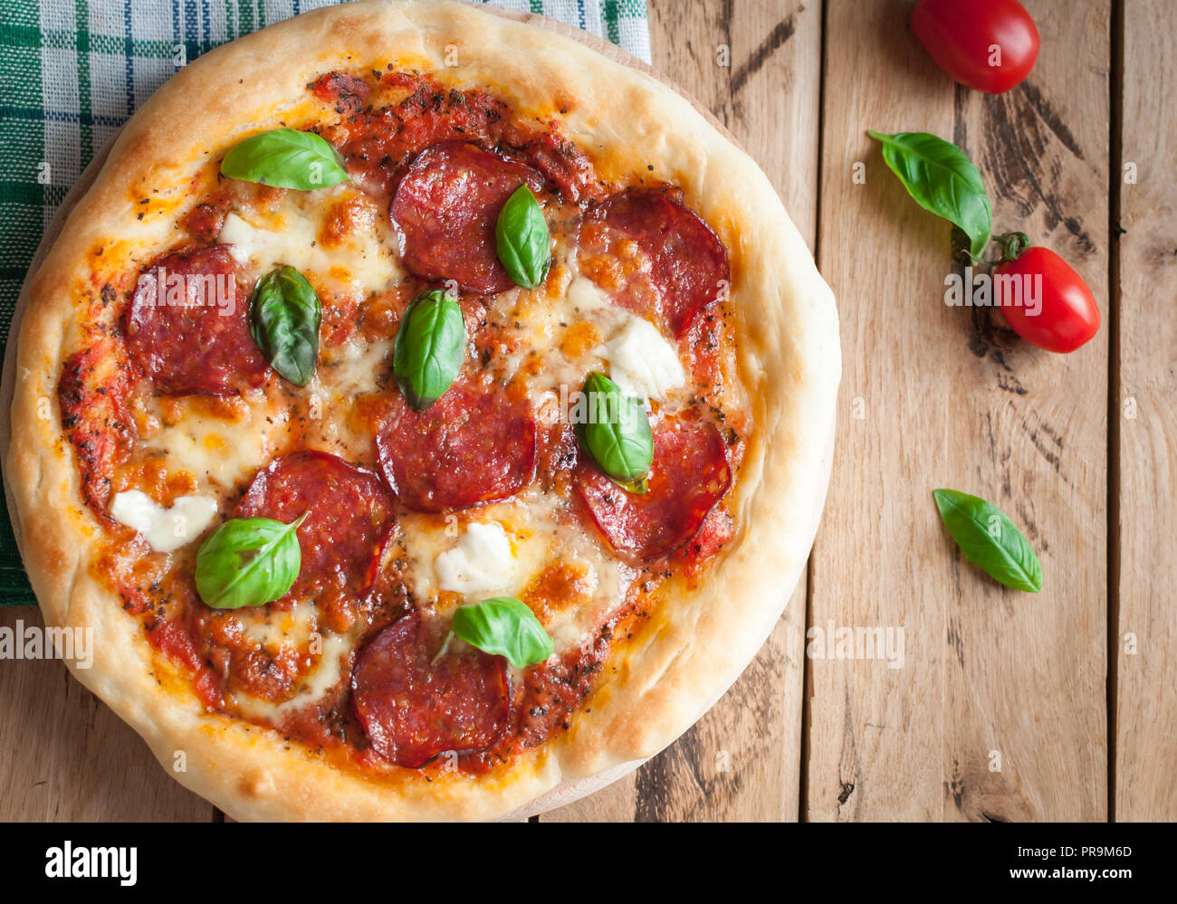 Nahaufnahme der hausgemachten rustikale Pizza mit Salami, Mozzarella und frischem Basilikum, Ansicht von oben Stockfoto