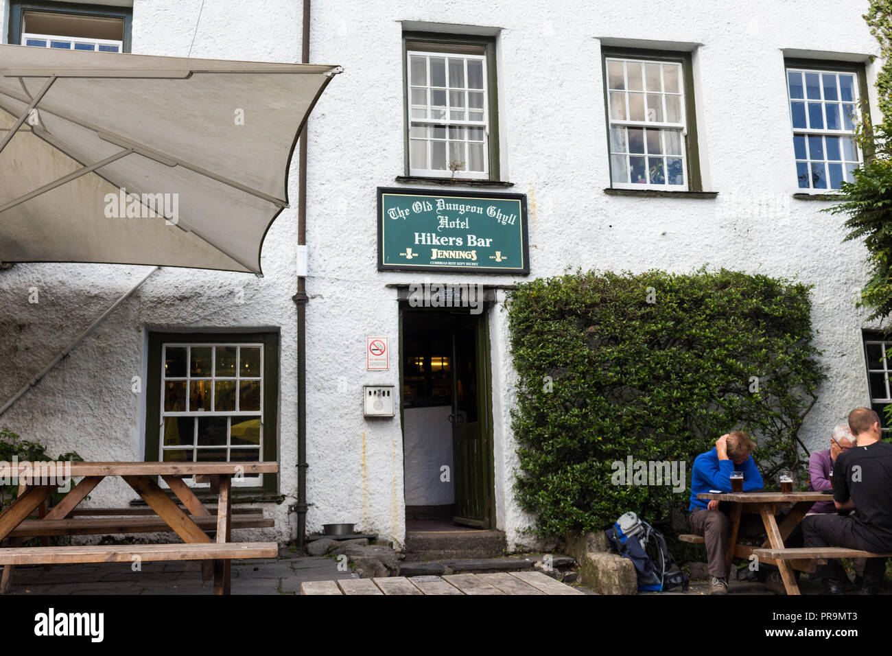 Hillwalkers entspannten Bier trinken außerhalb des Alten Dungeon Ghyll Hotel Wanderer Bar, Great Langdale, Lake District, Cumbria, England. Stockfoto