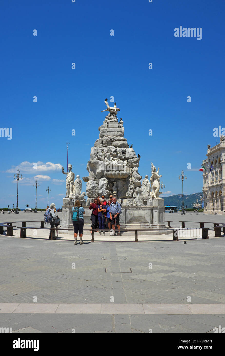 Touristen stehen durch den Brunnen (Fontana dei Quattro Continenti) an der Piazza Unita d'Italia, Triest, Italien, während ein anderer Tourist ihr Foto. Stockfoto