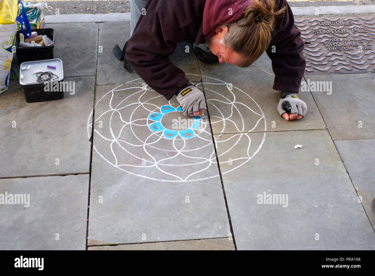 Artist Beginn seiner Mandala auf dem Bürgersteig zu machen. Glastonbury, Somerset, Großbritannien Stockfoto