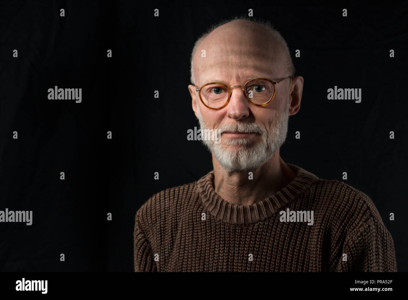 Portrait von älteren Mann an der Kamera schaut auf schwarzem Hintergrund Stockfoto