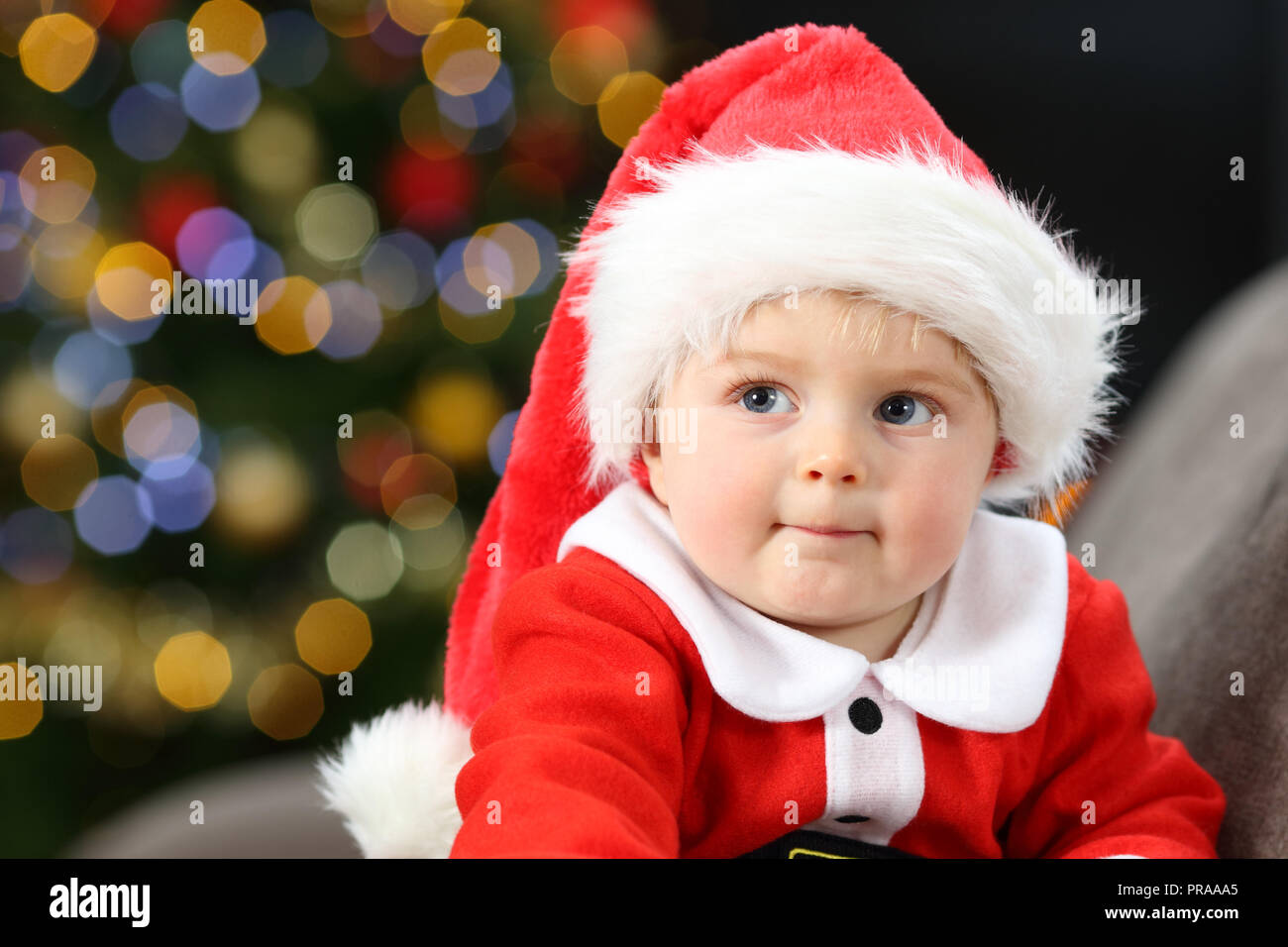 Nachdenklich Baby Tragen santa claus Kostüm auf einer Couch zu Hause in Weihnachten Stockfoto