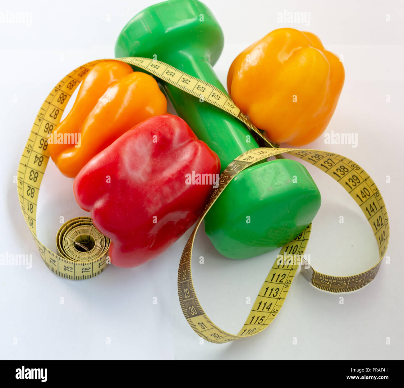 Maßband und Pfeffer auf einem weißen Hintergrund. Fitness Hanteln Stockfoto