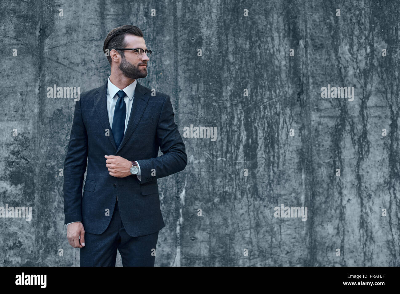 Ein junger Geschäftsmann mit Brille und Bart sieht auf der linken Seite Stockfoto