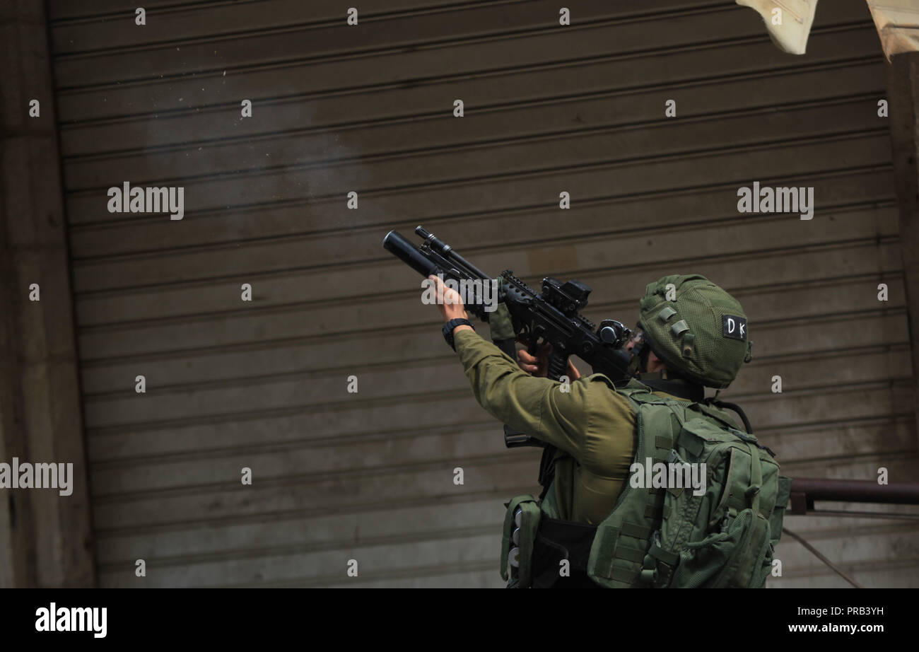 Hebron, West Bank Stadt Hebron. 1. Okt, 2018. Ein israelischer Soldat feuert Tränengas Kanister auf palästinensische Demonstranten während der Auseinandersetzungen nach einem Protest gegen die kürzlich beschlossenen jüdischen Nationalstaat, in der West Bank Stadt Hebron, am Okt. 1, 2018. Credit: Mamoun Wazwaz/Xinhua/Alamy leben Nachrichten Stockfoto