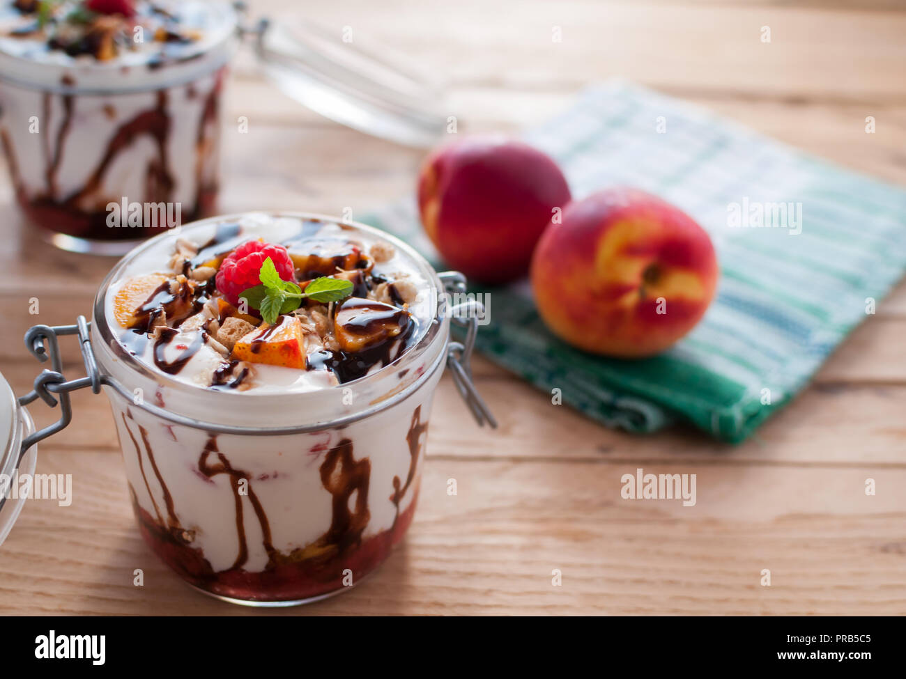 Close-up von Peach Parfait mit Joghurt, Müsli und Schokolade in einem Glas nachfüllen Stockfoto