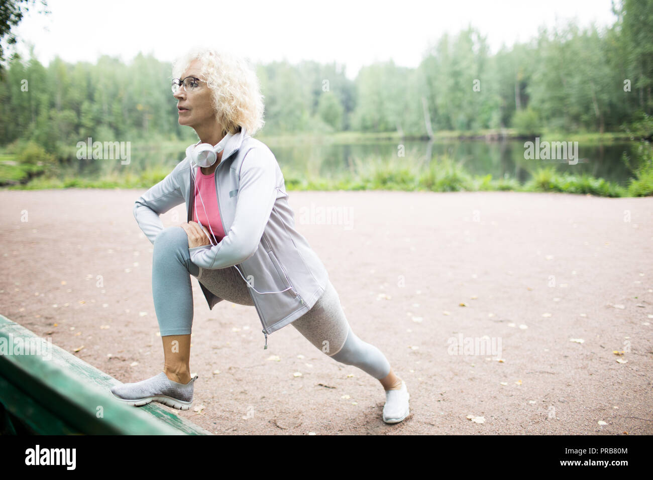 Im Alter von energetischen weiblich in Sportkleidung zu tun stretching Übung in natürlicher Umgebung Stockfoto