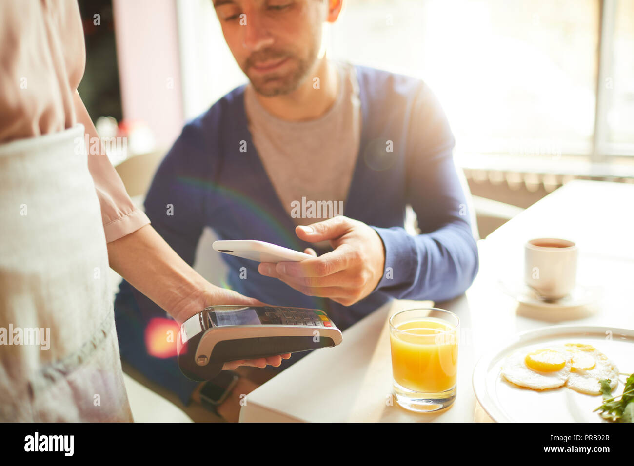 In der Nähe von schöner Mann, Bill durch Smartphones und Gerät an Cash Terminal durch die Kellnerin im Café statt Stockfoto