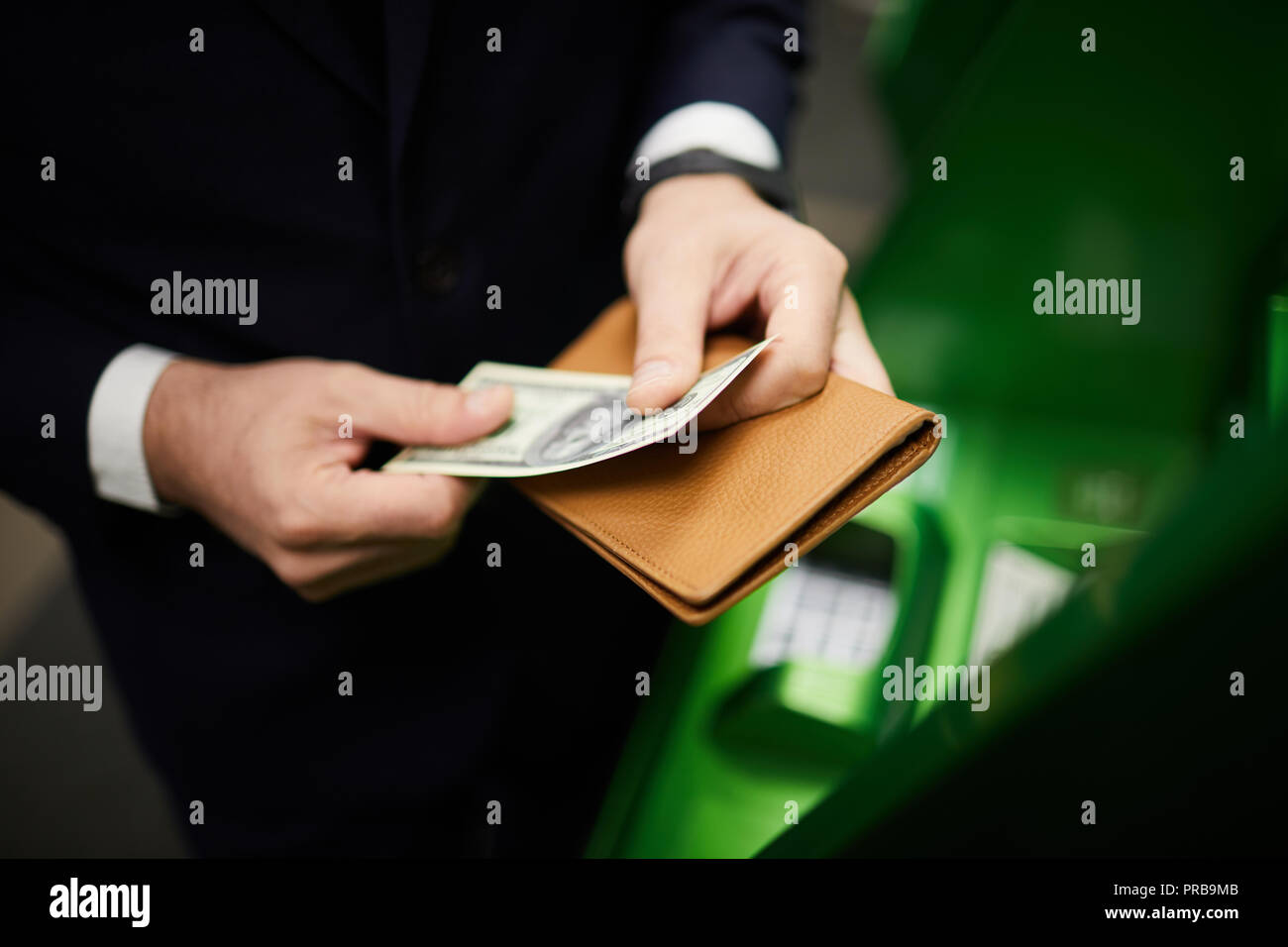 Geschäftsmann Holding dollar Banknote und Lederetui stehend von Bargeldterminals Stockfoto