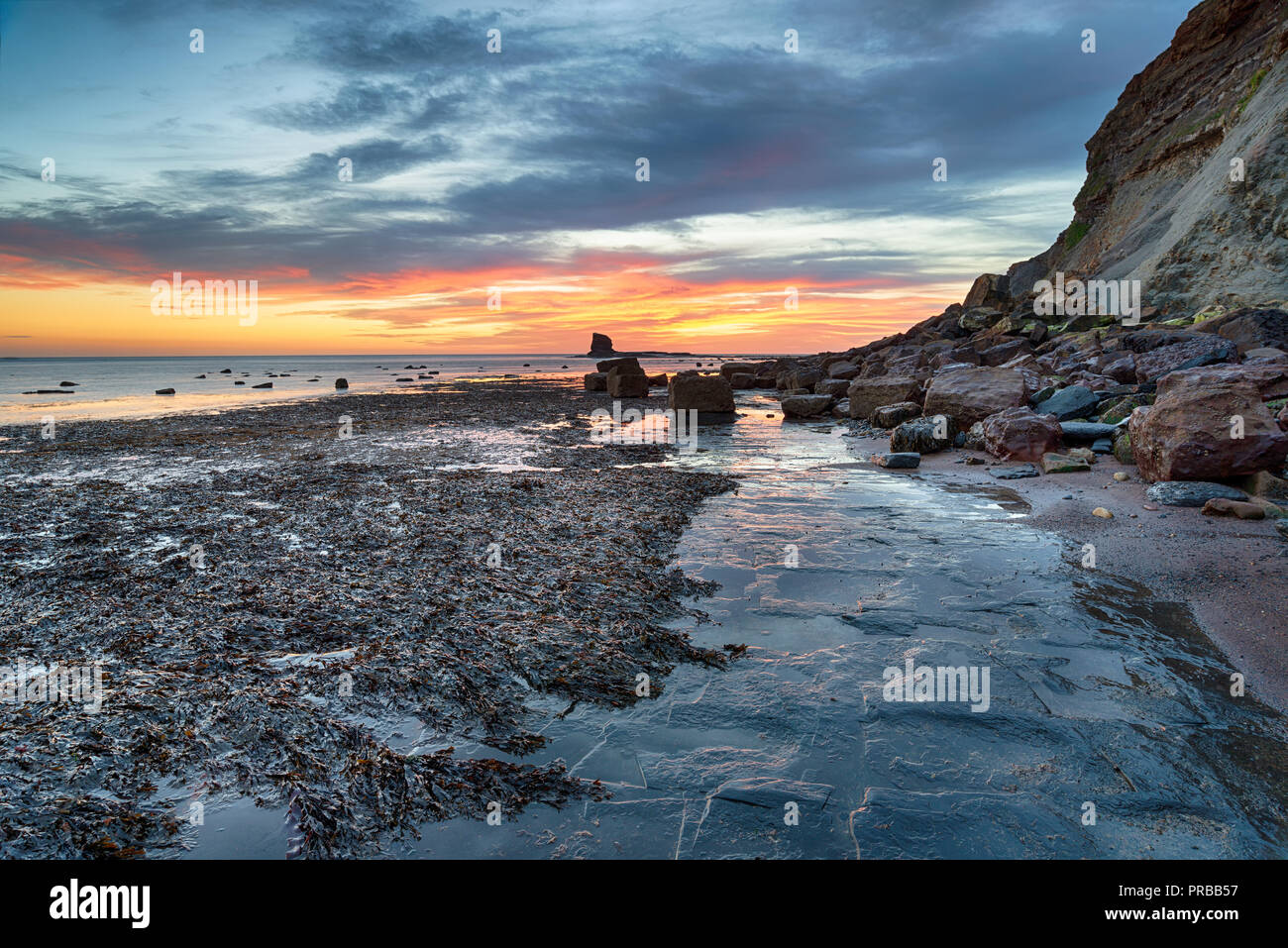 Atemberaubenden Sonnenaufgang über dem felsigen Strand bei Saltwick Bucht auf der Yorkshire Küste in der Nähe von Whitby Stockfoto