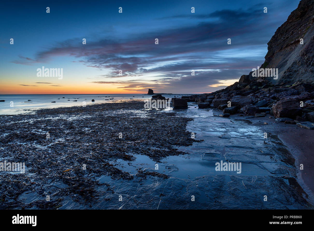 Atemberaubenden Sonnenaufgang über Saltwick Bucht ausserhalb von Whitby an der Küste von North Yorkshire Stockfoto