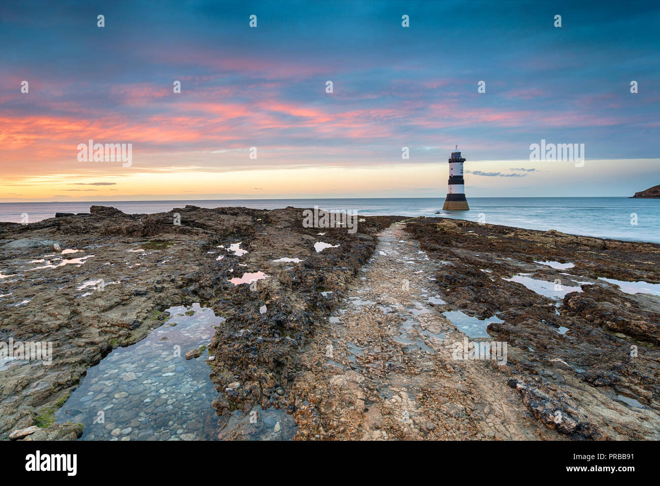 Einen schönen Sonnenuntergang am Leuchtturm auf Penmon Trwyn Du Point in der Nähe von Beaumaris auf Anglesey in Wales Stockfoto