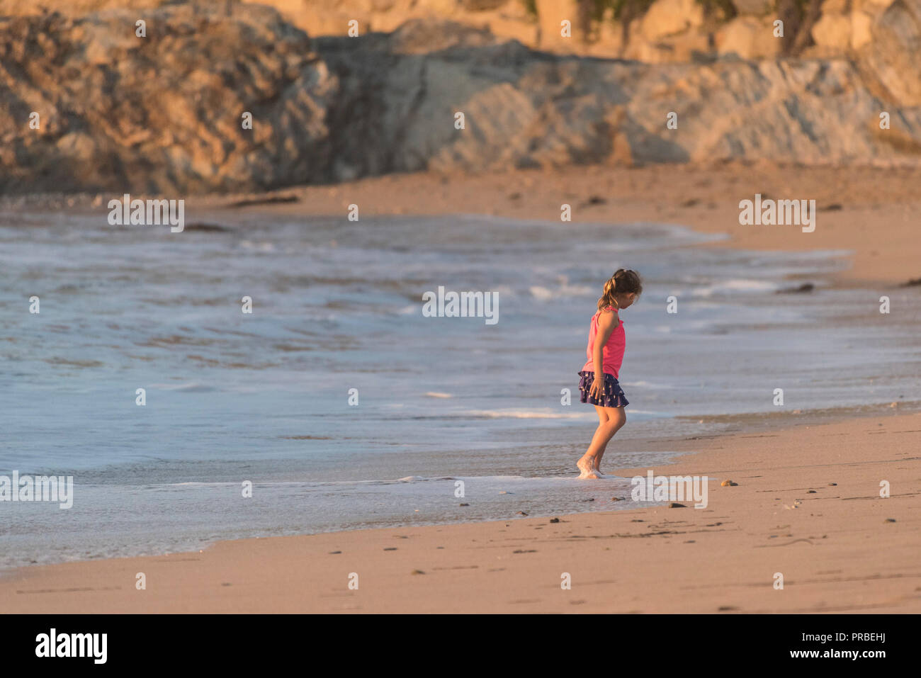 Ein junges Mädchen, das während eines Aufenthalts in der Strandpromenade von Fistral in Newquay in Cornwall alleine unterwegs ist. Stockfoto