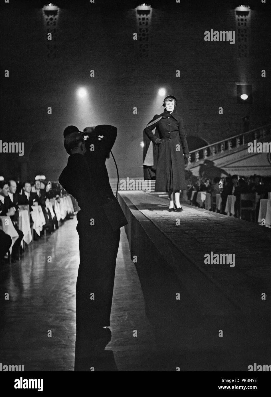50er Jahre Mode. Ein fashion model ist zu Fuß auf den Laufsteg. Die Silhouette eines photograher in der Front zeigt ihm die Kamera auf ein Foto des Modells. Schweden 1952. Ref bei 42-9 Stockfoto