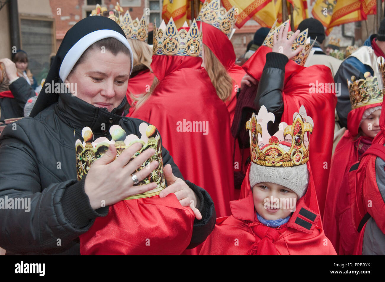Nonne Kinder helfen mit ihrem Papier Kronen vor Kavalkade der Heiligen Drei Könige, Heilige Drei Könige Urlaub Prozession, Krakau, Polen Stockfoto
