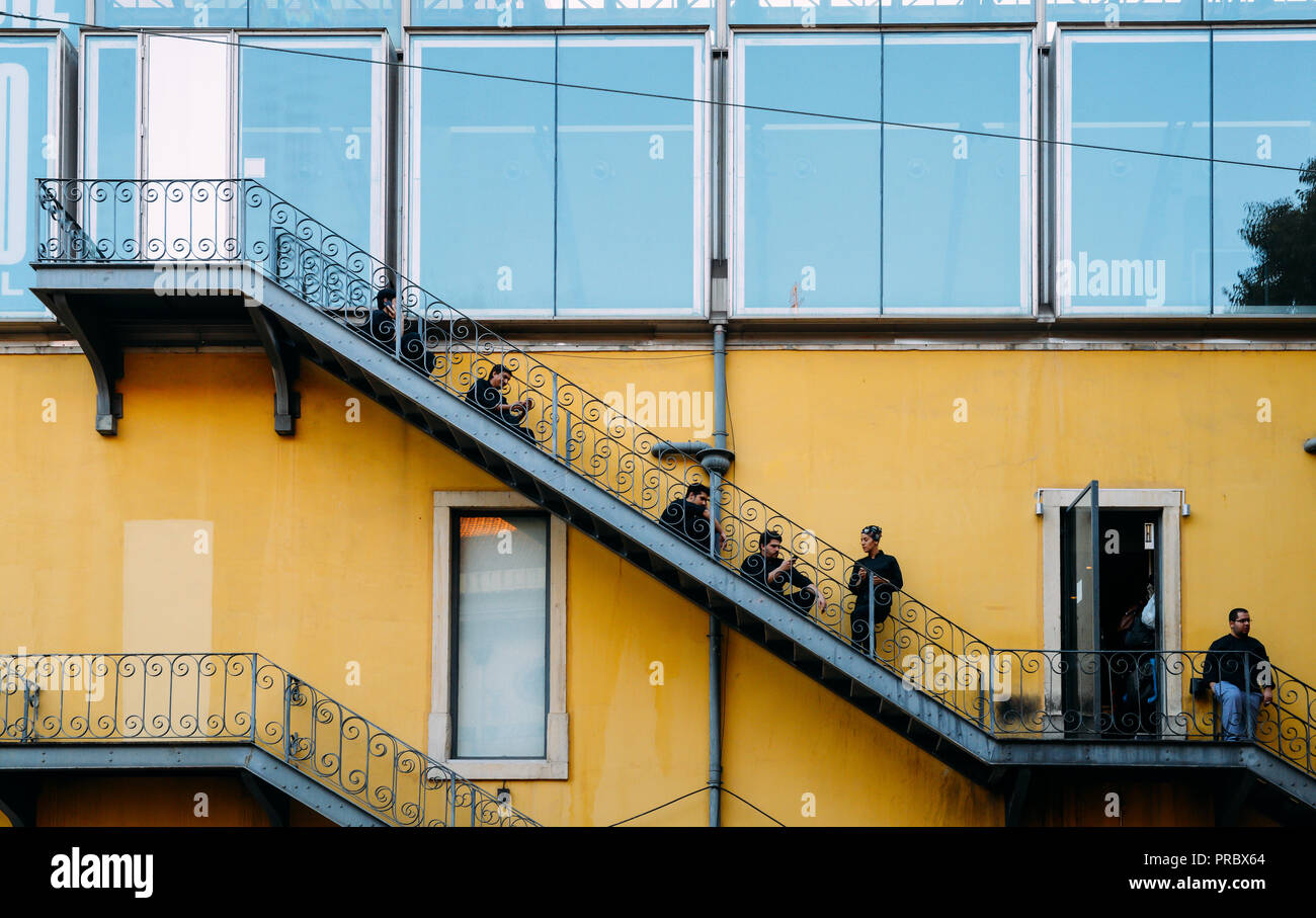 Lissabon, Portugal - Sept 28, 2018: Arbeiter in Uniform ihre Smartphones zu überprüfen und eine Zigarette Pause auf einer klassischen Brand Treppen in Lissabon Stockfoto