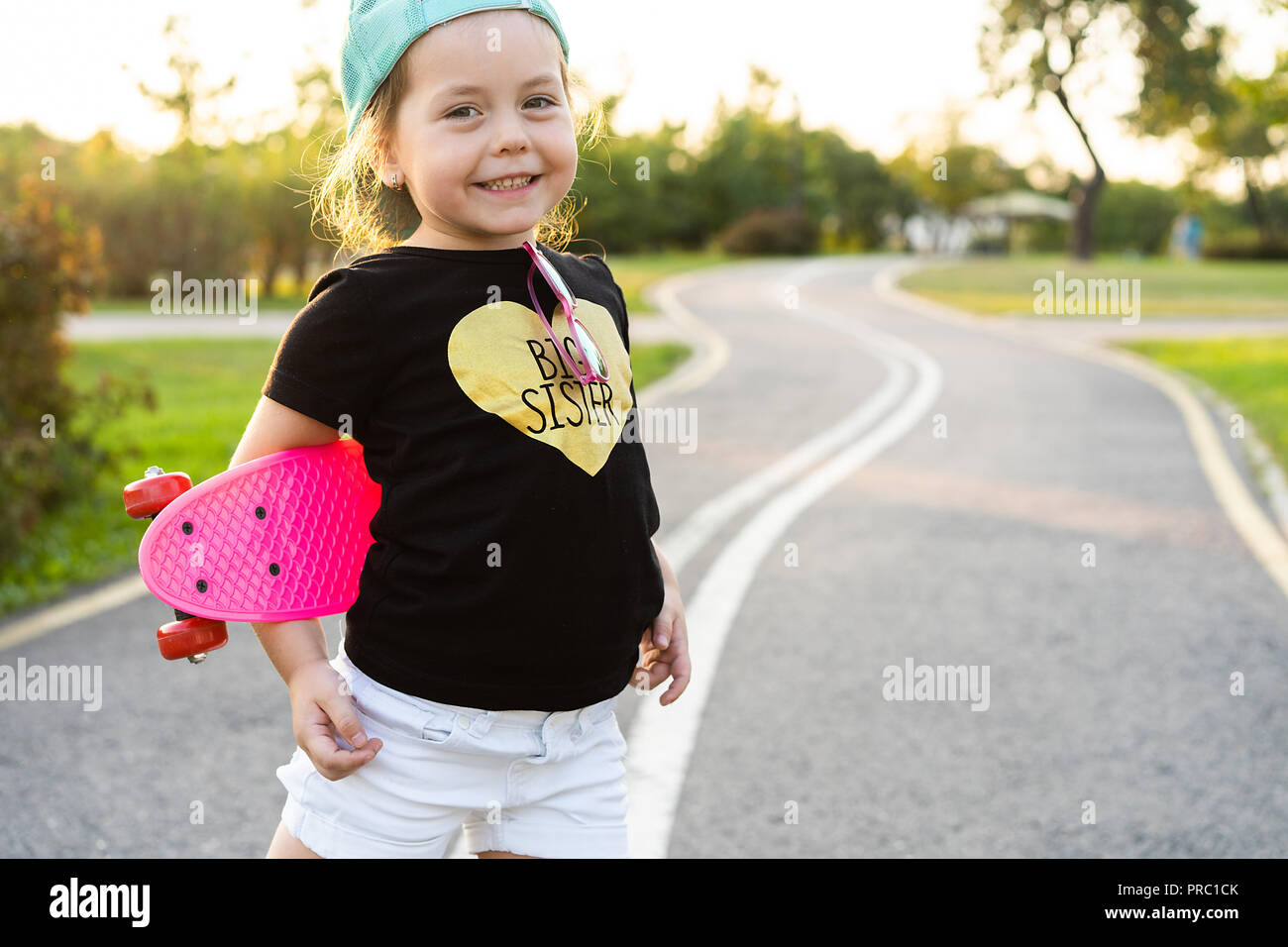 Mode Mädchen Kind mit Skateboard das Tragen einer Sonnenbrille und hipster Shirt. Stockfoto