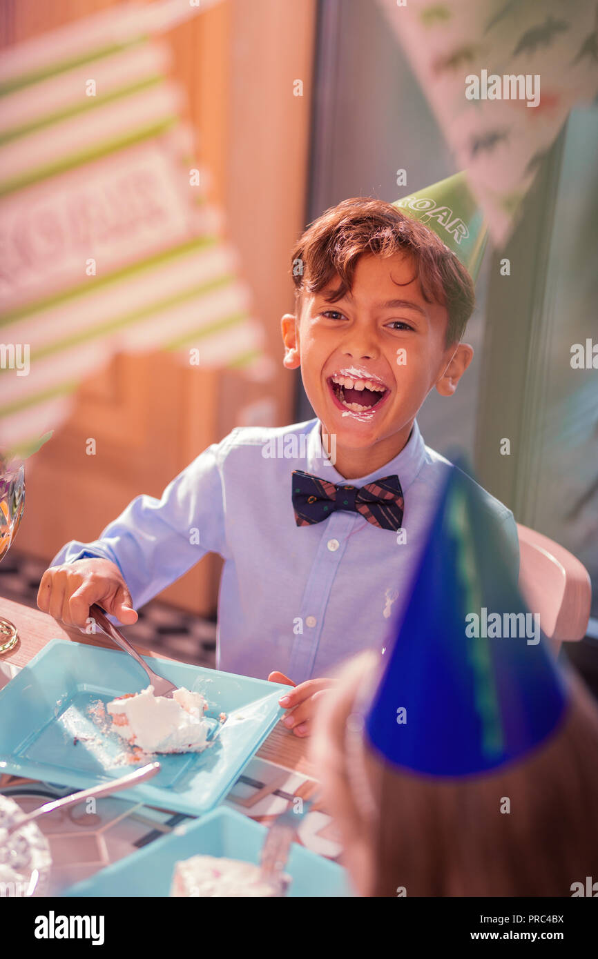 Junge mit schmutzigen Mund lacht während der Kuchen essen Stockfoto