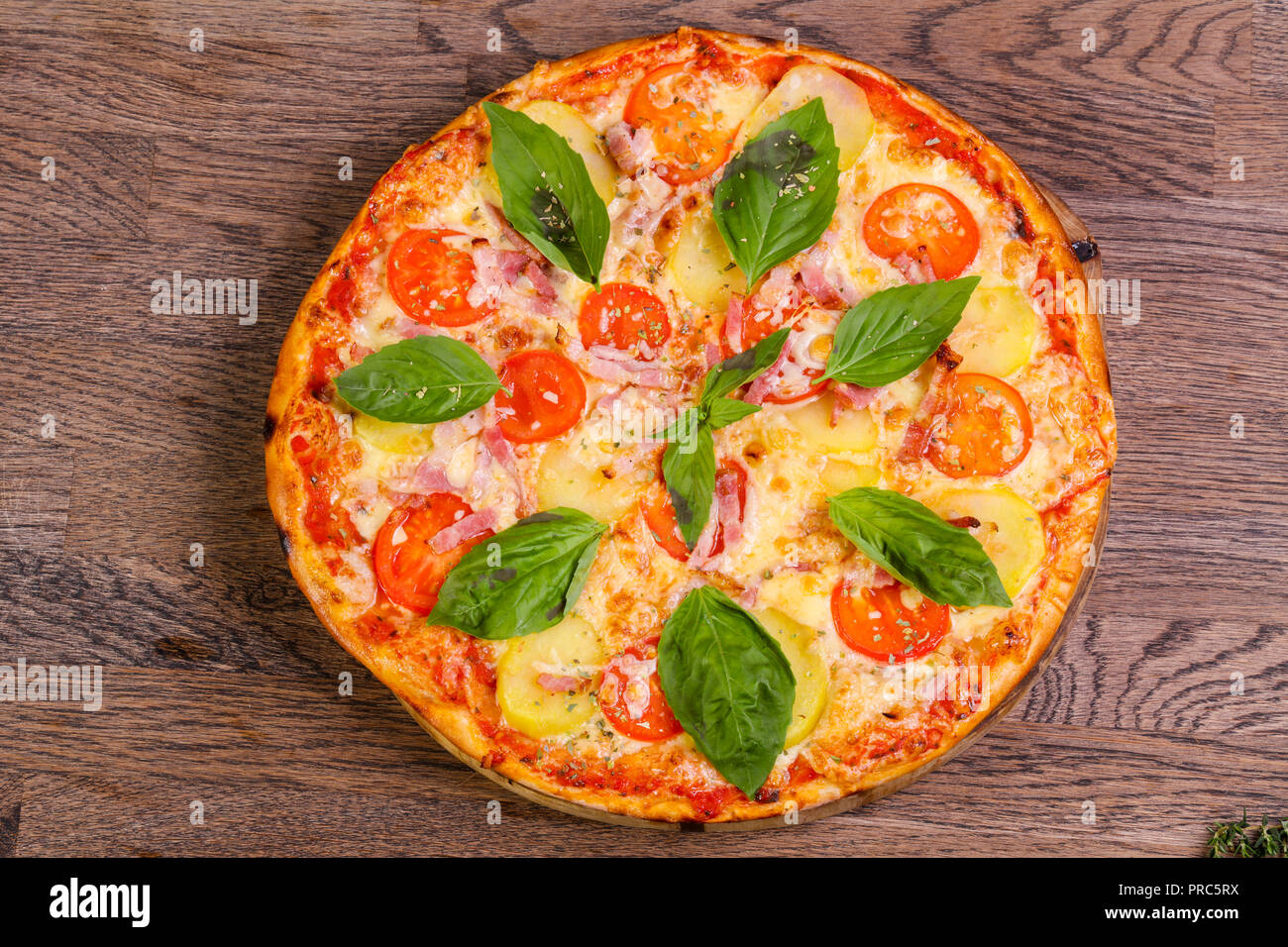 Pizza mit Schinken und Kartoffeln serviert Basilikum Stockfoto