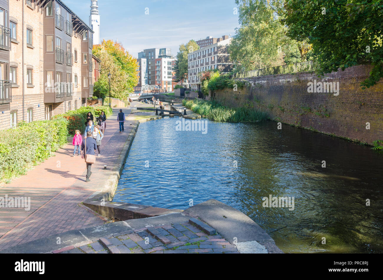 Menschen zu Fuß entlang des Kanals Leinpfad an Cambrian Wharf, Birmingham im Herbst Sonnenschein Stockfoto