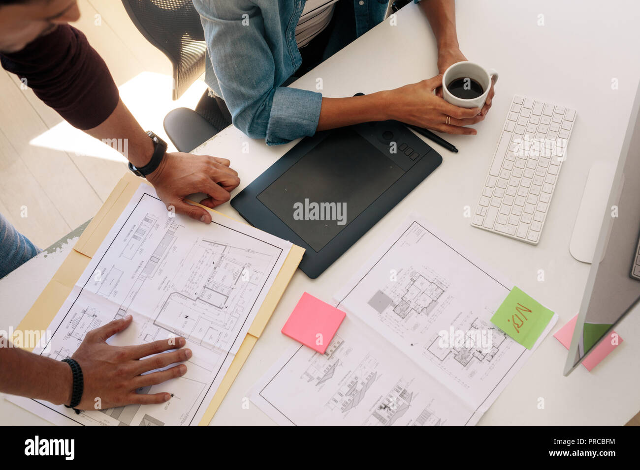 Blick von oben auf die beiden Kollegen bei Architektur Pläne sitzt vor einem Computer. Mann am Schreibtisch mit einem Plan während seiner Begleiterin Stockfoto