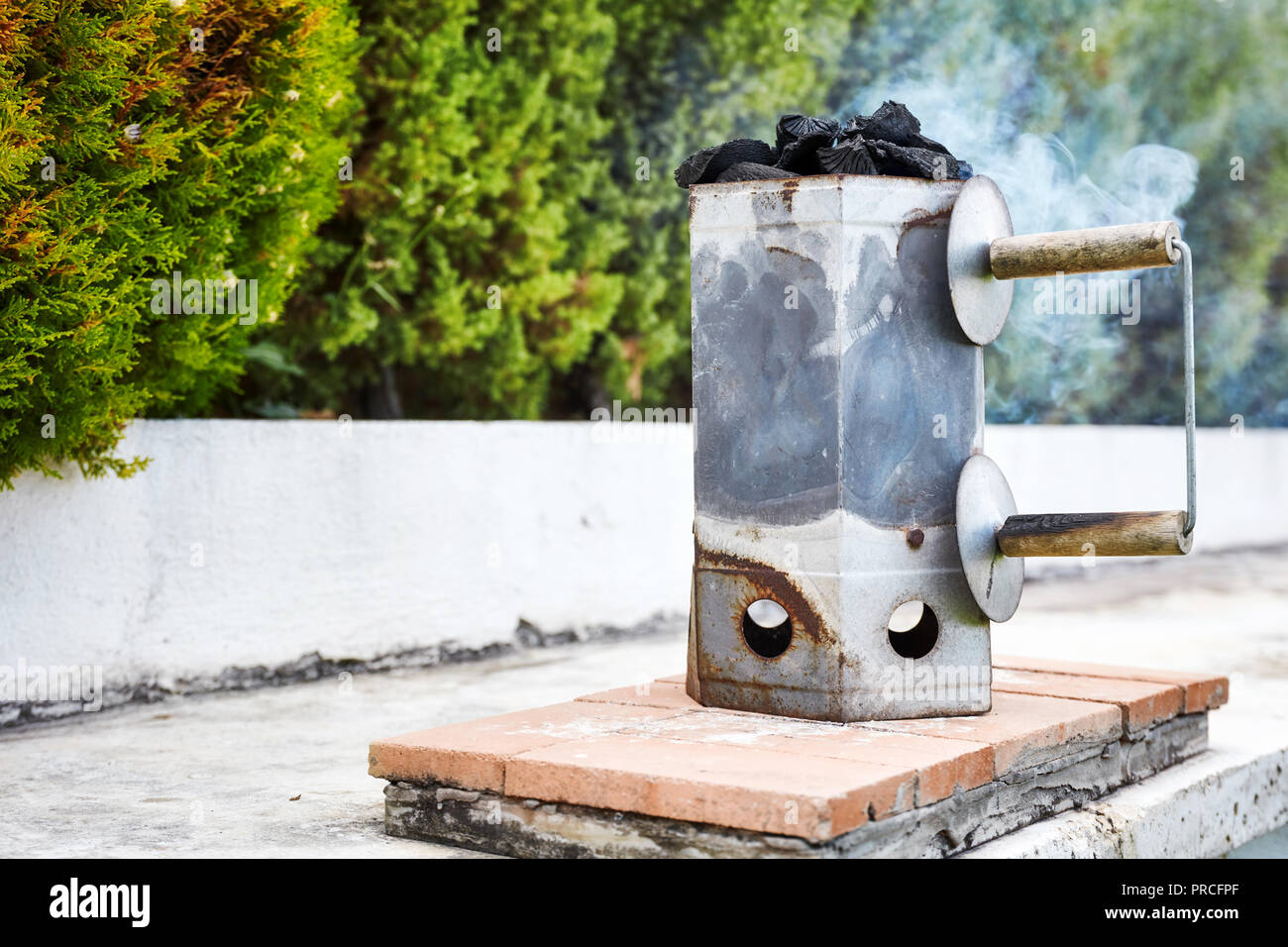 Rauchen Holzkohle Chimney Starter Schaufel für Grill in einem Garten im Hinterhof Stockfoto
