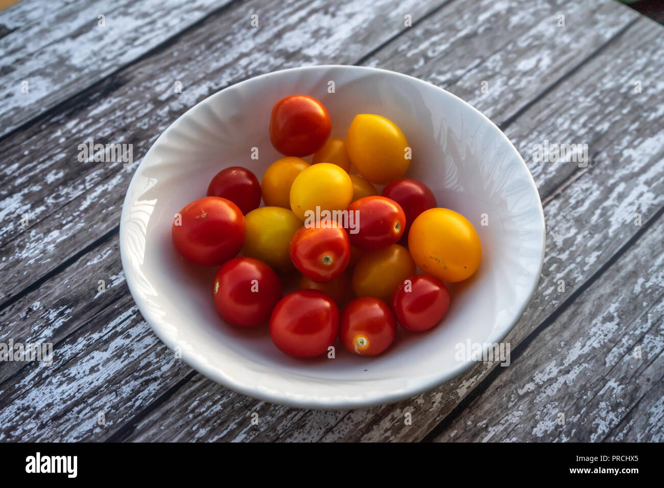 Eine Schüssel gemischten roten und gelben kleinen Tomaten auf einem Holztisch Stockfoto