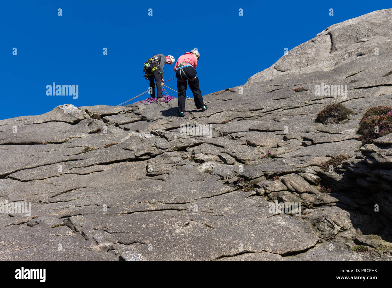 Ein Mädchen abseilen unten einen Felsen mit einem Instruktor. Hen Berg, Mourne Mountains, N. Irland. Stockfoto