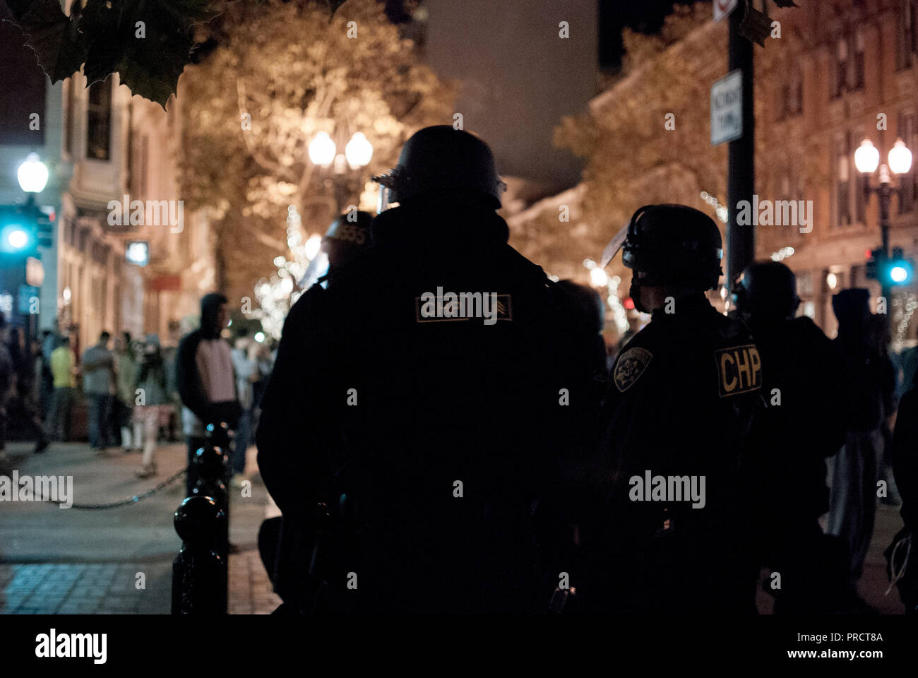 California Highway Patrol Offiziere beobachten Demonstranten in der Nähe der Ecke zur 9. und Washington Straßen in der Innenstadt von Oakland nach Donald Trump Wahl. Stockfoto