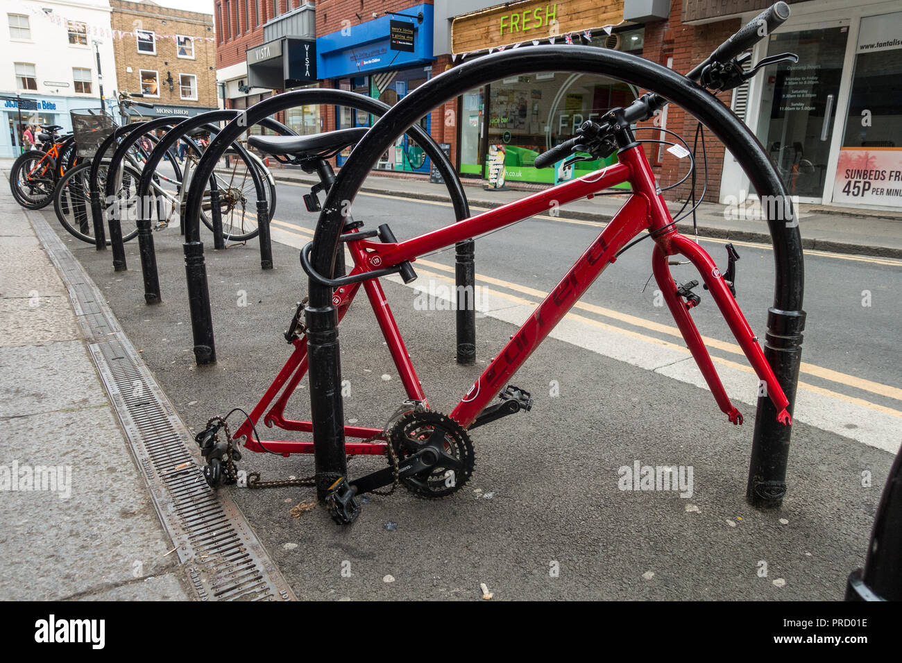 Ein Rad, das bis zu einem Fahrradträger in Windsor gesperrt ist hat Räder in einem Akt der Kleinkriminalität gestohlen. Der Rahmen ist links verlassen. Stockfoto