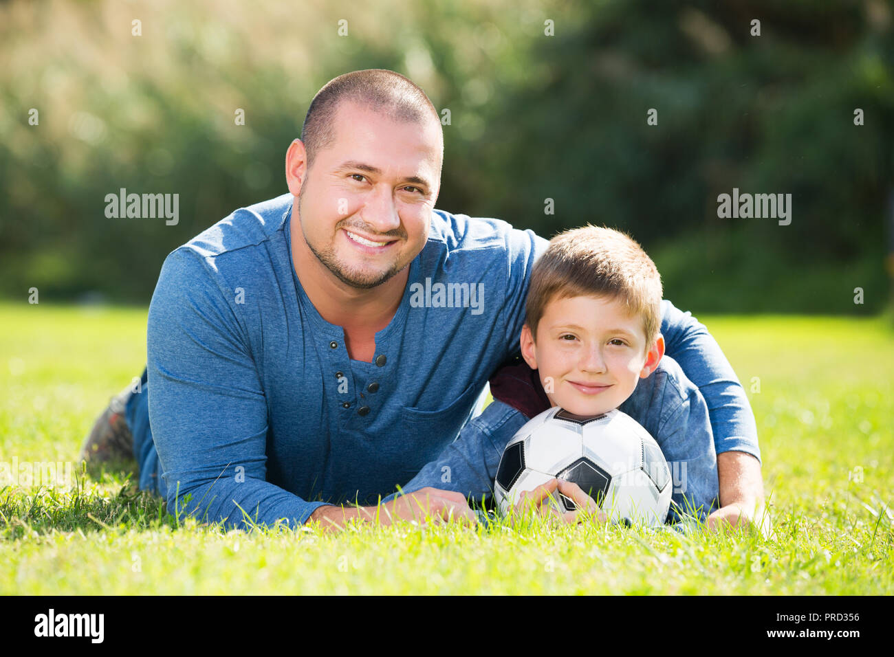 Portrait von Vater und Sohn mit Fußball auf Gras Stockfoto